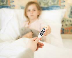 Wiederherstellung nach Krankheit. wenig Mädchen geben ihr Mutter Digital Thermometer nach Messung Temperatur. foto