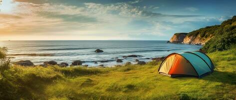 Camping Zelt und Camping Ausrüstung auf Grün Gras mit Meer Aussicht Hintergrund ai generiert foto