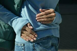 weiblich Hände mit ein schön Maniküre Nahansicht auf das Hintergrund von ein Blau Sweatshirt und Jeans. foto