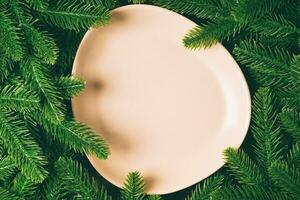 Draufsicht der runden festlichen Platte auf Tannenbaumhintergrund. weihnachtsgerichtkonzept mit leerem raum für ihr design foto