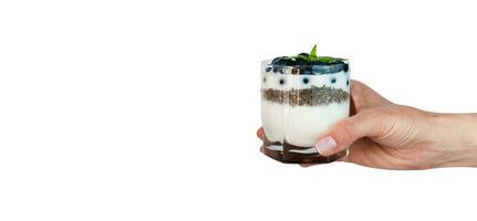 Frau Hand hält ein Glas von Dessert mit Joghurt, frisch Blaubeere und Chia Saat isoliert auf Weiß Hintergrund. köstlich und gesund Frühstück. Banner. Kopieren Raum. foto