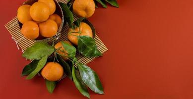 Reife helle rohe Mandarinen auf Zweig mit grünen Blättern in einer Schüssel foto