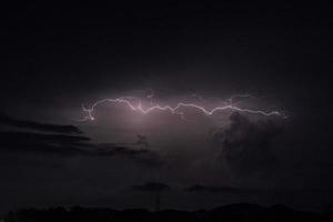 Blitzschlag in der dunklen Nacht mit der Regenwolke foto