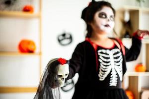 verschwommenes Porträt asiatisches kleines Mädchen in Halloween-Kostüm mit Schädel