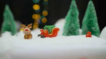 Spielzeug Hirsch auf das Hintergrund von das Weihnachten Baum. Weihnachten Hintergrund mit ein Hirsch und Schlitten. süß Weihnachten Elch mit Geschenk Kisten auf das Schlitten auf schneebedeckt Landschaft Hintergrund. foto