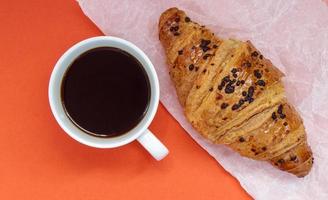 schwarzer Kaffee ohne Milch in einer weißen Tasse und einem Schokoladencroissant foto