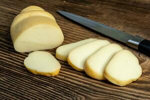 geräuchert schwer Käse auf ein hölzern Tafel mit ein Messer foto