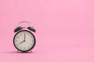 Uhr mit Uhrzeit auf rosa Hintergrund foto