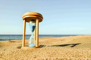 ein Sanduhr auf das Strand mit Blau Sand foto