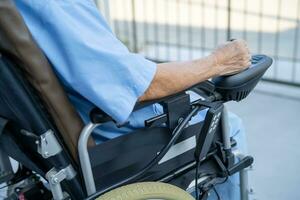 asiatisch Senior Frau geduldig auf elektrisch Rollstuhl mit Fernbedienung Steuerung beim Krankenhaus, gesund stark medizinisch Konzept. foto