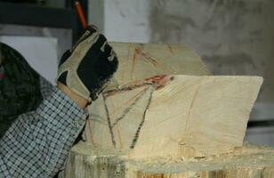 Belluno Italien - - 11 01 2023 Handwerker mit Bleistift im Hand während Messung ein Stück von Holz zu erstellen ein Statue foto