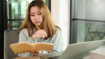 Teenager-Frau mit Bleistift und Notizbuch ernste Geste mit Laptop. foto