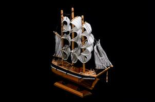 ein hölzern Modell- von ein Segeln Schiff auf ein schwarz Hintergrund foto