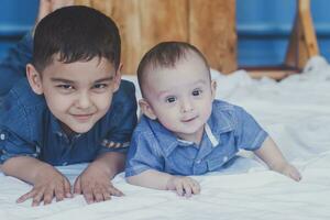 glücklich Kindheit Konzept. glücklich Brüder Porträt. 6 Jahre und 6 Monate alt Jungs haben Spaß. zwei wenig Kinder lächelnd haben gut Zeit. süß wenig Brüder Lügen und spielen zusammen foto