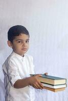 zurück zu Schule Konzept. süß Mitte östlichen Junge halten ein Stapel von Bücher gegen das Weiß Hintergrund. Porträt von zentral asiatisch Kind vorbereiten zu gehen zu Schule foto