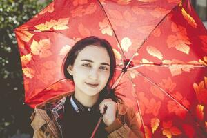 Porträt von ein ziemlich Frau im sonnig und warm Herbst oder Frühling Tag posieren mit das Regenschirm foto