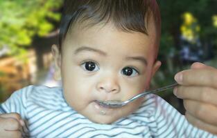 Essen von Löffel von sechs Monat asiatisch Baby foto