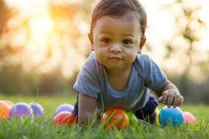 süß asiatisch Baby kriechen im das Grün Gras und bunt Ball foto