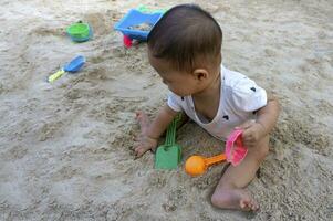 asiatisch Kleinkind Baby thailändisch Mädchen spielen mit Sand foto