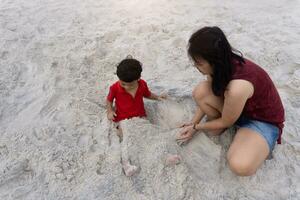 asiatisch Familie Sohn und Mutter abspielen Sand auf das Strand foto