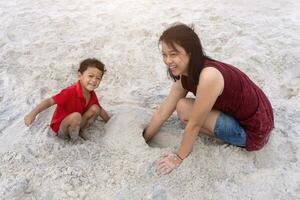 asiatisch Familie Sohn und Mutter abspielen Sand auf das Strand foto