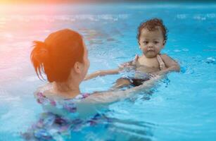 Baby Junge zuerst Zeit im ein Schwimmen Schwimmbad foto