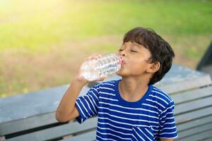 Kind Trinken Wasser von ein transparent Plastik Flasche. foto