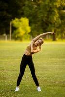 ziemlich jung Frau Dehnen im das Park foto