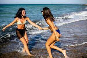 zwei ziemlich jung Frau haben Spaß auf das Strand foto