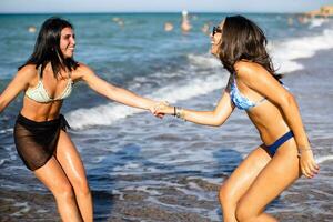 zwei ziemlich jung Frau haben Spaß auf das Strand foto