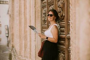 weiblich Tourist mit Stadt Karte durch das Kirche san francesco dassisi im Ostuni, Italien foto