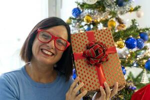 schön glücklich Frau beim Zuhause im das Weihnachten Atmosphäre unter Baum und Geschenke foto