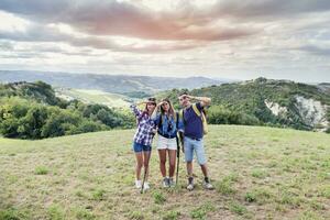 Gruppe von jung Erwachsene sieht aus zu das Horizont während Wandern foto