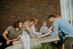 Gruppe von jung Menschen und Kinder Essen Pizza im das Haus Hinterhof foto