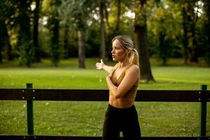 ziemlich jung Frau Dehnen im das Park foto