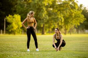 zwei ziemlich jung Frauen Dehnen im das Park foto