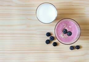 eben legen von gesund trinken, hausgemacht Blaubeere Smoothies und ein Glas von Milch mit frisch Blaubeeren auf hölzern Tabelle Hintergrund foto