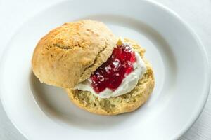 scone mit Sahne und Kirsche Marmelade auf das Teller foto