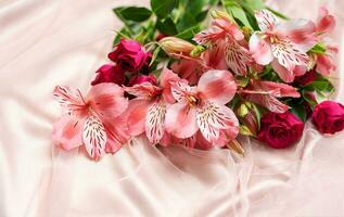 schön Alstroemeria und Rosen auf Rosa Seide Hintergrund. foto