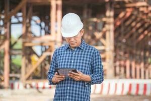 Ingenieur Mann mit Digital Tablette Überprüfung Projekt beim das Gebäude Grundstück, Vorarbeiter Arbeiter beim Infrastruktur Konstruktion Seite? ˅ foto