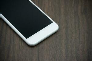 Clever Telefon im Weiß Farbe mit leer Bildschirm auf hölzern Tisch. foto
