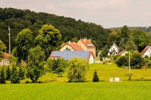 ein Grün Feld mit Häuser und Solar- Paneele foto