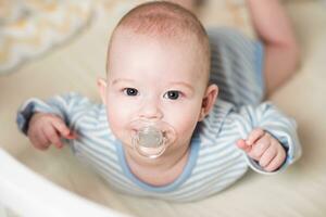 das Baby Lügen im ein Krippe auf seine Bauch. foto