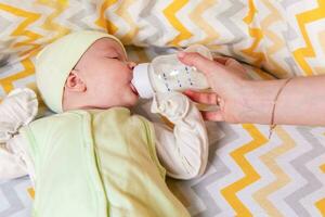 Mutter Einspeisungen ein Neugeborene Baby mit Milch von ein Flasche foto