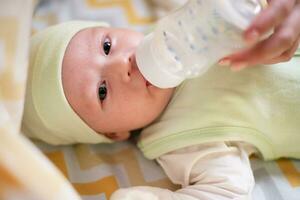 jung Mutter Einspeisungen ihr Baby Milch von ein Flasche foto