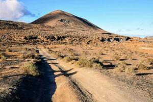 das Schmutz Straße führt zu ein Berg im das Mitte von das Wüste foto