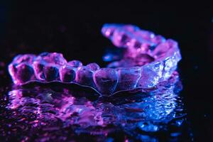 transparent Aligner, Zahn Halter Lüge auf ein Spiegel mit Wasser Tröpfchen auf ein schwarz Hintergrund foto