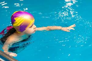 klein Kind schwimmen im ein Innen- Schwimmbad. foto