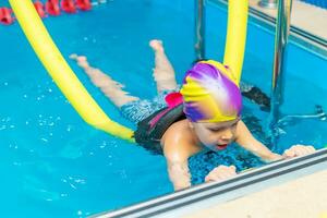 klein Kind schwimmen im ein Innen- Schwimmbad. foto