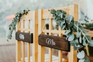 Stühle zum Braut und Bräutigam dekoriert mit Blumen mit Zeichen Herr und Frau zum Hochzeit Zeremonie foto